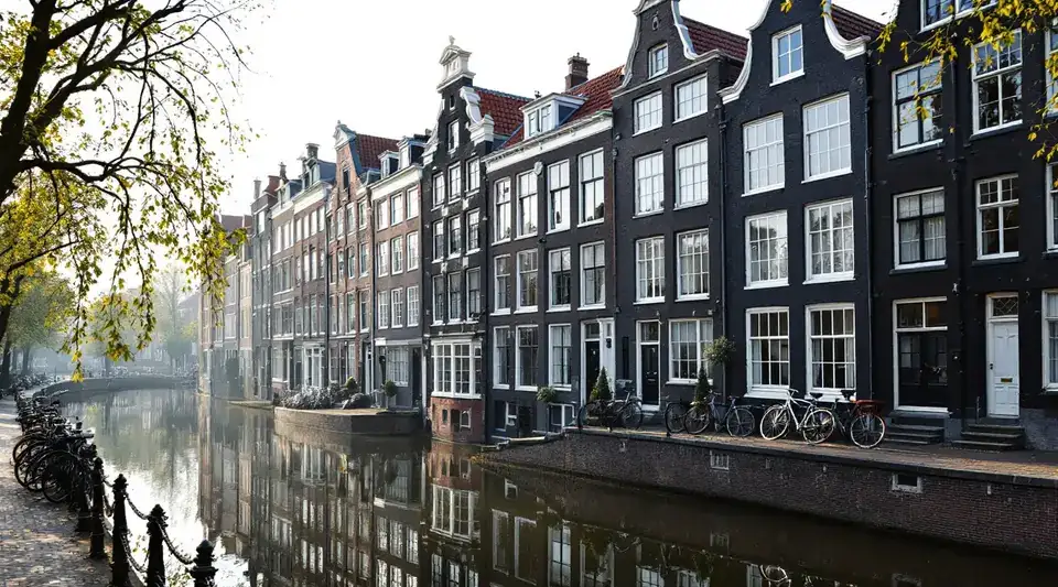 Een rij smalle grachtenpanden met trapgevels, halsgevels en klokgevels die spiegelen in het water, met fietsen tegen de reling